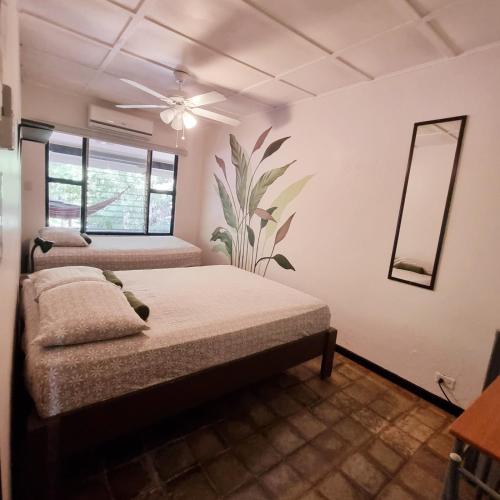 a bedroom with two beds and a mirror at Casa Pura Vida Surf Hostel - Tamarindo Costa Rica in Tamarindo