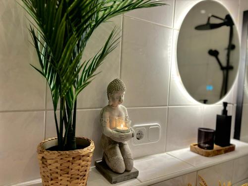 a statue of a person holding a candle on a bathroom counter at Das Luxusnest in Bad Ems
