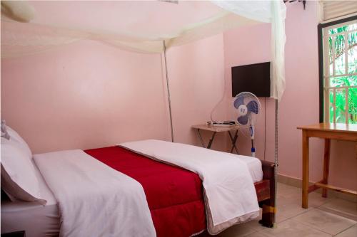 a bedroom with a bed with a red and white blanket at Tgs Homestay Nest in Kampala