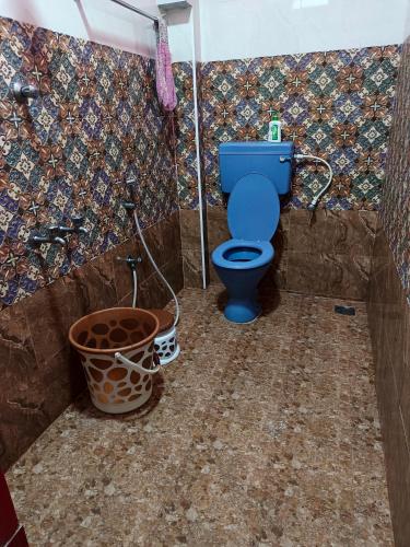 a bathroom with a blue toilet and a bucket at La Baie Homestay in Pondicherry