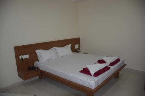 a bed with white sheets and red towels on it at Shrinivas Lodge in Dhārwād