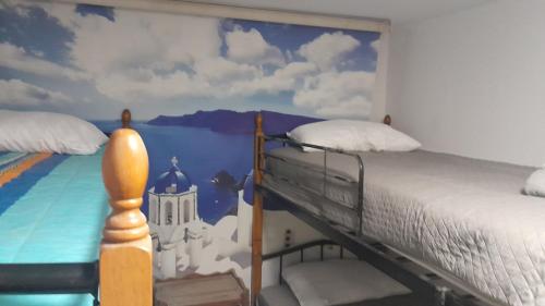 una camera da letto con un letto e un dipinto sul muro di The Rabbit Hole Hostel Fira a Firà