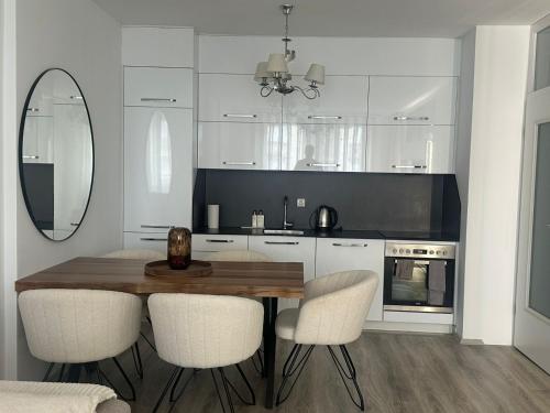 a kitchen with a wooden table and white cabinets at BT Apartments in Kosovo Polje