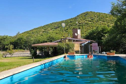 zwei Personen in einem Schwimmbad mit einem Berg im Hintergrund in der Unterkunft Casa Entera in Cordoba