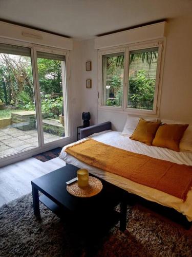 une chambre avec un grand lit et deux fenêtres dans l'établissement Charmant Studio au Cœur de Boulogne avec jardin, à Boulogne-Billancourt