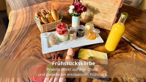 a tray of food with a basket of bread and a bottle of juice at Chalet WaldHäusl luxuriöse Ferienwohnungen mit Sauna & Whirlpool, Kamin, Balkon oder Terrasse mit Bergblick in Heiligenblut