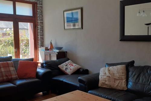 un salon avec un canapé en cuir noir et une table dans l'établissement The Old Coach House, à Belle-Isle-en-Terre