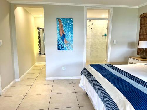 a bedroom with a bed and a painting on the wall at Beach Melody, Umdloti South Beach, king Bed in Umdloti
