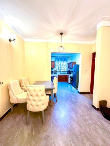 a living room with a table and chairs and a kitchen at Teddy Homestay in Makindye