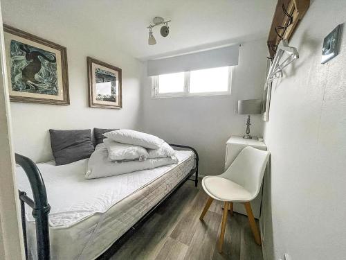 a small bedroom with a bed and a chair at Lovely 4 Berth Chalet At Cedar Springs Park In Heacham, Norfolk Ref 92031Cs in Heacham