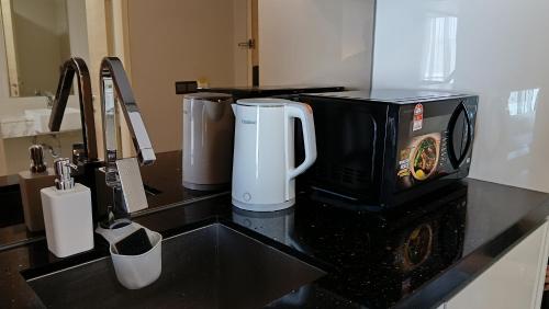 a bathroom counter with a sink with a coffee maker at The Straits Suites by Ciconia in Melaka