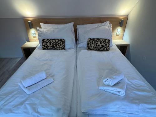 a white bed with two pillows and towels on it at Apartmány Formanka na náměstí in Hustopeče