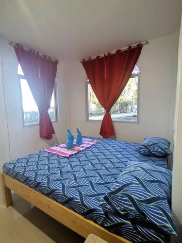 a bedroom with a bed with blue comforter and windows at House with Sunrise&Beach view in Candaping B