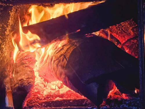 a fire inside of a fireplace with flames at Reindeer Lodge Very Special Retreat With Private Hot Tub Near Cannock Chase By StayStaycations in Colton
