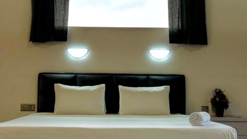 a bed with a black headboard and white pillows at Liora Homestay in Gelioya