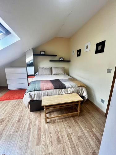 a bedroom with a bed and a wooden table at DÚPLEX DUQUESA in O Barco de Valdeorras