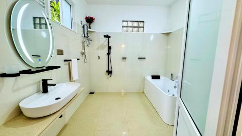 a white bathroom with a sink and a mirror at Liora Homestay in Gelioya