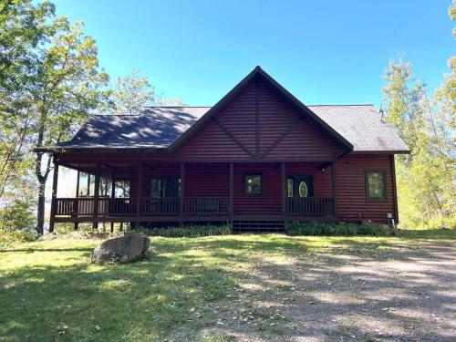 een groot houten huis met een grote veranda bij Welcome to Bear's Den Lodge in Round Lake Seaplane Base
