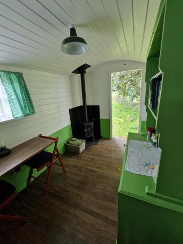 科姆堡The Delkin Shepherds Huts Castle Combe的客房设有壁炉、桌子和炉灶。