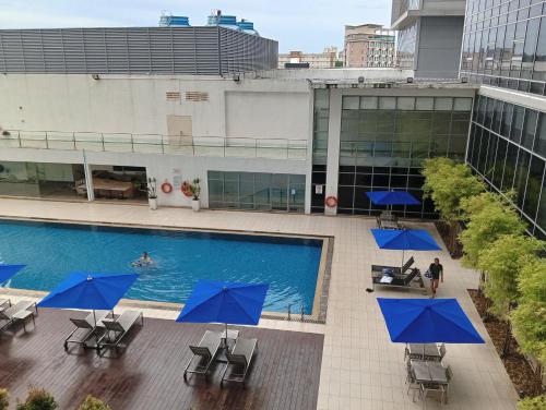 an overhead view of a pool with blue umbrellas at The Straits Suites by Ciconia in Melaka