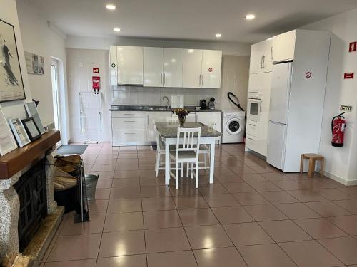 a kitchen with white cabinets and a table and chairs at Casa de Casarelhos - "Gerês" - Estúdio piso 0 - Apartamento Piso 1 in Geres