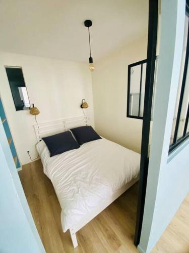 un lit blanc dans une chambre avec deux fenêtres dans l'établissement Charmant 2 pièces, hyper centre Mâcon, à Mâcon