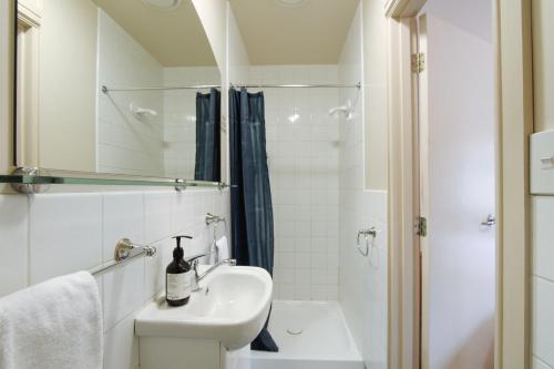 a white bathroom with a sink and a shower at The Grand Hotel & Bar - Akaroa in Akaroa
