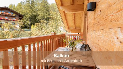 a wooden porch with a table on a deck at Chalet WaldHäusl luxuriöse Ferienwohnungen mit Sauna & Whirlpool, Kamin, Balkon oder Terrasse mit Bergblick in Heiligenblut