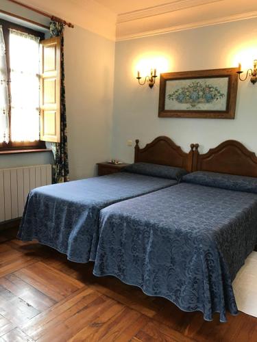 a bedroom with a bed with a blue blanket at Hotel Rural Villa Elena in Panes