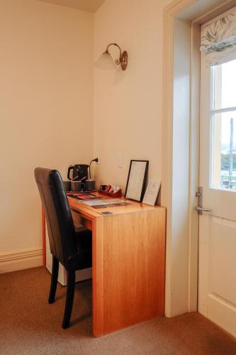 a wooden desk with a chair next to a window at The Grand Hotel & Bar - Akaroa in Akaroa
