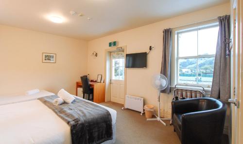 a bedroom with a bed and a desk and a window at The Grand Hotel & Bar - Akaroa in Akaroa