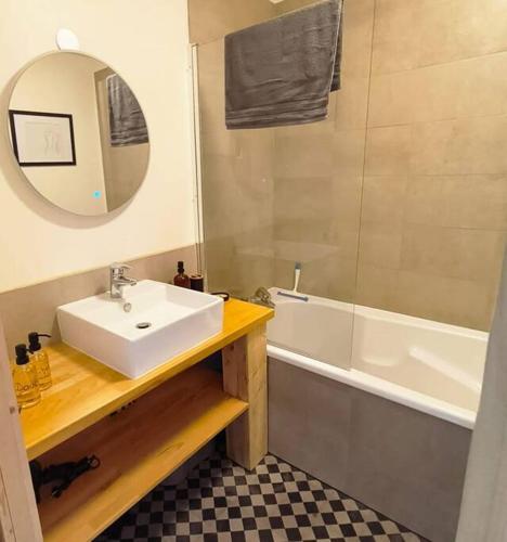 une salle de bain avec un lavabo, une baignoire et un miroir dans l'établissement Le Jean-Paule, à Jallieu