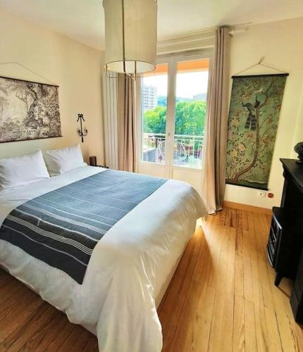 une chambre avec un grand lit et une grande fenêtre dans l'établissement Le Jean-Paule, à Jallieu