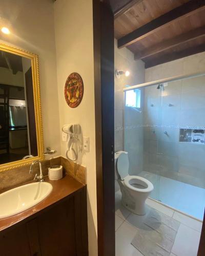 a bathroom with a sink and a toilet and a mirror at Pousada Morrison in Praia do Rosa