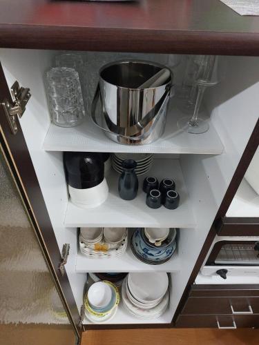 a cupboard with a pot and plates and bowls at つきびとはうす in Satte