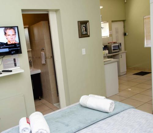 a room with a bed and a kitchen with a tv at Art and Accommodation Guesthouse in Cape Town