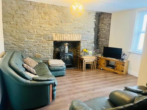 a living room with a couch and a stone wall at Rj s house in Merthyr Tydfil