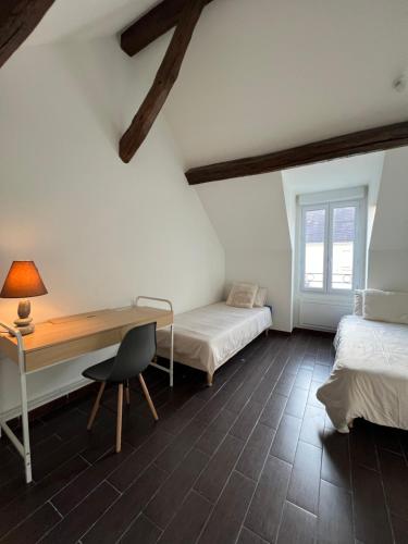 Cette chambre comprend deux lits, un bureau et une table. dans l'établissement Beau duplex T3 bis bien situé, à Sens