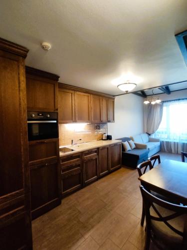 a kitchen with wooden cabinets and a table and a couch at 7 Pools SPA Boutique Hotel in Bansko