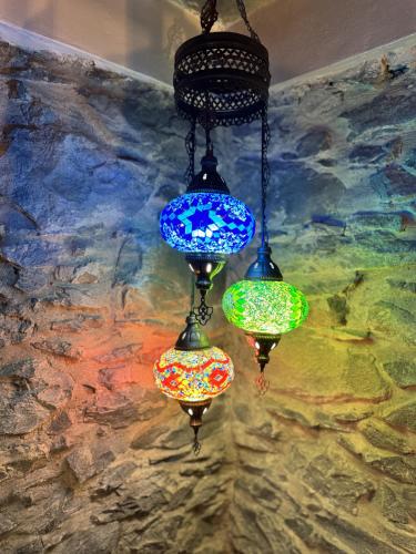 three colorful glass lights hanging from a wall at Victoria Tiny Stone House in Ponta do Pargo