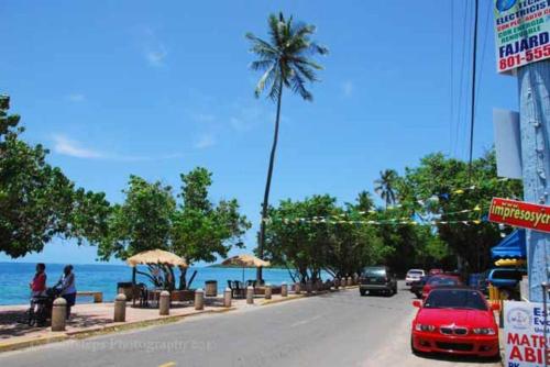 a street with cars driving down a street with a palm tree at Cozy apartment near the beach #2 in Fajardo