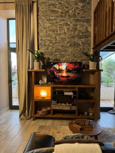 a living room with a tv and a stone wall at Victoria Tiny Stone House in Ponta do Pargo