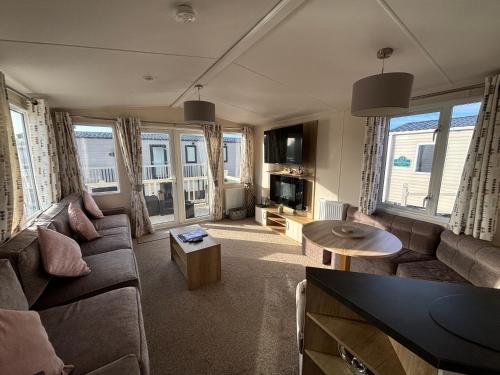 ein Wohnzimmer mit Sofa und Tisch in der Unterkunft Palm Grove 121 - Golden Palm Resort - Pet friendly, WiFi, close to beach and clubhouse - Meadow Lakes Caravan & Lodge Hire in Chapel Saint Leonards