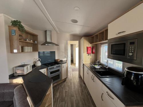 eine kleine Küche mit einer Arbeitsplatte und einer Mikrowelle in der Unterkunft Palm Grove 121 - Golden Palm Resort - Pet friendly, WiFi, close to beach and clubhouse - Meadow Lakes Caravan & Lodge Hire in Chapel Saint Leonards