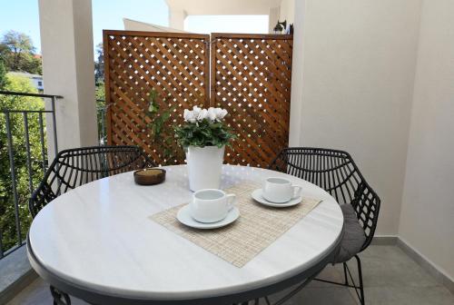 a white table with two cups and a vase with flowers at Marousos Central Guesthouse in Portariá