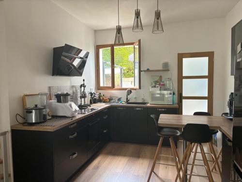 une cuisine avec des placards noirs, une table et une fenêtre dans l'établissement Maison de ville impériale, à Compiègne