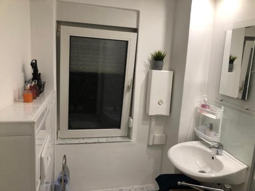 a white bathroom with a sink and a window at Zentral Ferienwohnung P Siegen in Siegen