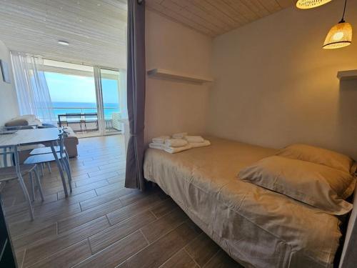 a bedroom with a bed and a table with a view of the ocean at Appartement 4 pers vue mer le barcares in Dosse Gros