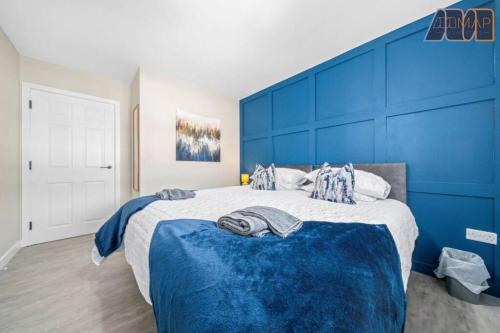 a bedroom with a large bed with a blue headboard at Elegant 2Bed Sleeps 4 With Parking in Paisley
