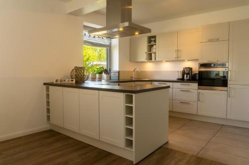 a kitchen with white cabinets and a black counter top at Haus Nordseequartier-Tating in Tating